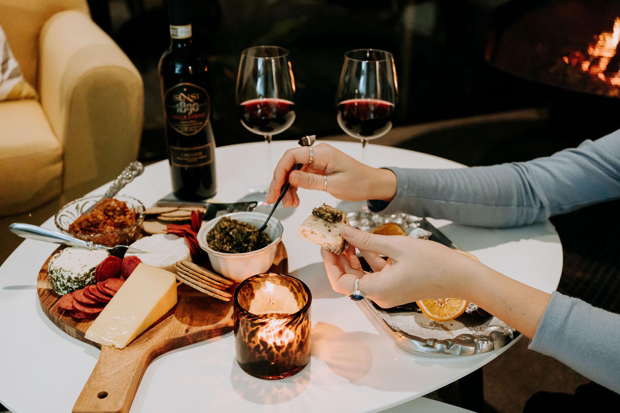 Woman enjoying a gourmet cheese board and red wine.