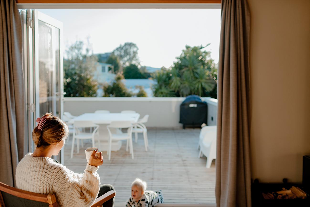 Young mother and toddler enjoy afternoon sun on a balcony at The Papamoa Pad holiday home in Papamoa.