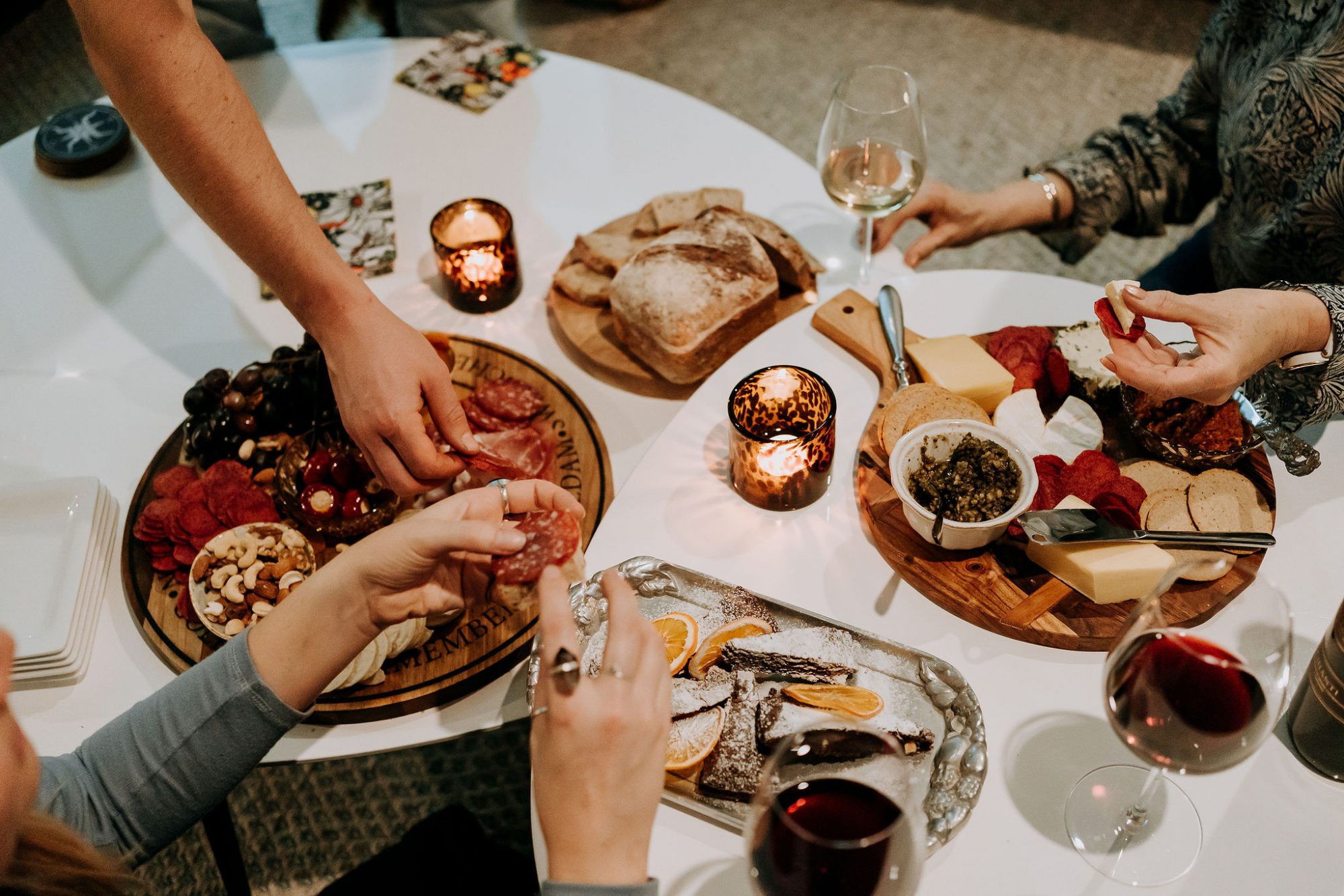 Friends enjoying a cheese, dessert and charcuterie boards with wine.