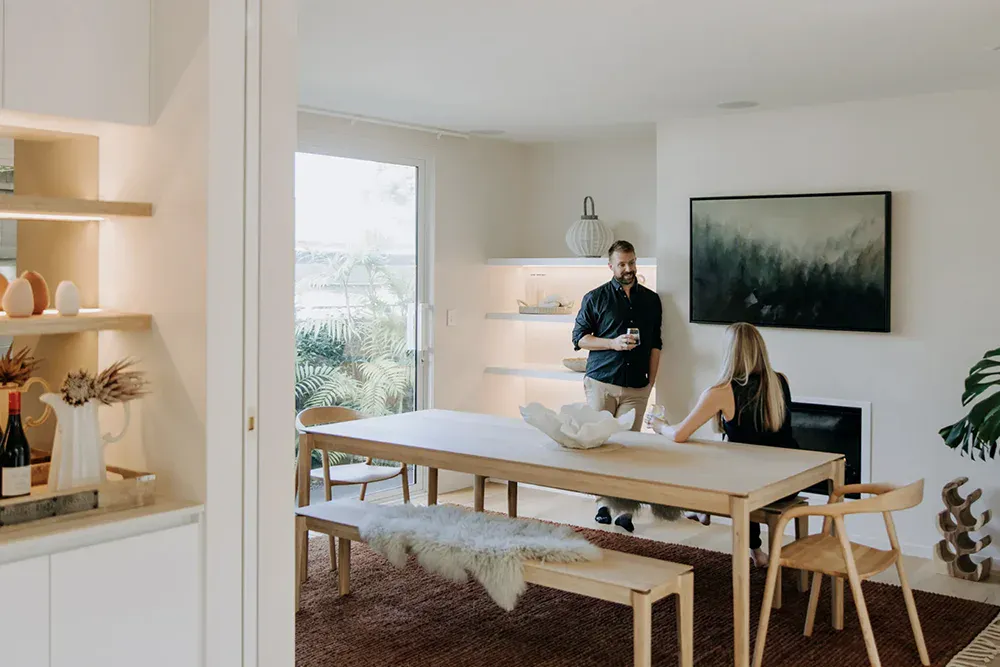 Young professional couple inside dining room talking and drinking.